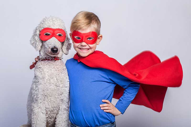 boy and dog wearing red eye masks and cape.